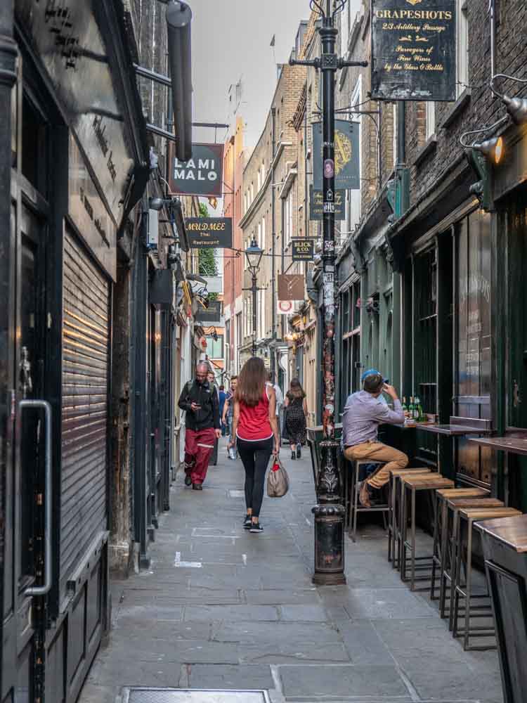 Shoreditch Artillery Lane. Woman walking man on barstool