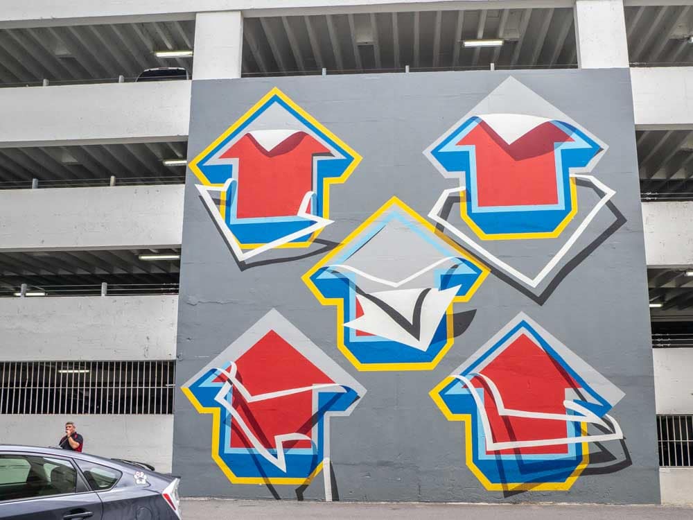 Mural Tavar Zawacki on parking lot wall- red and blue arrows
