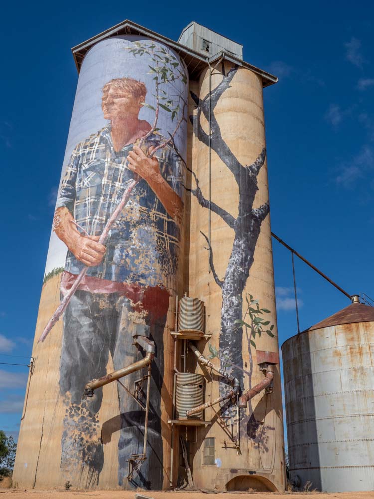 Patchewollack silo mural by Finatan Magee. Mural of farmer on grain silo.