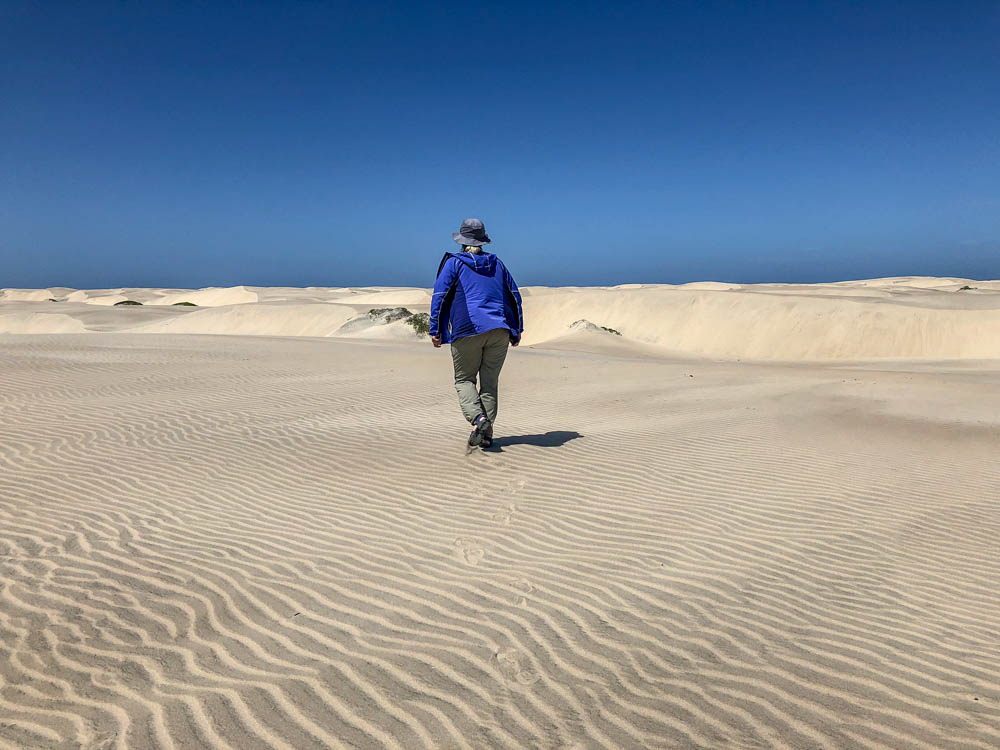 Magdalena Bay, Baja Mexico sand dunes. Woman in purple coat walking