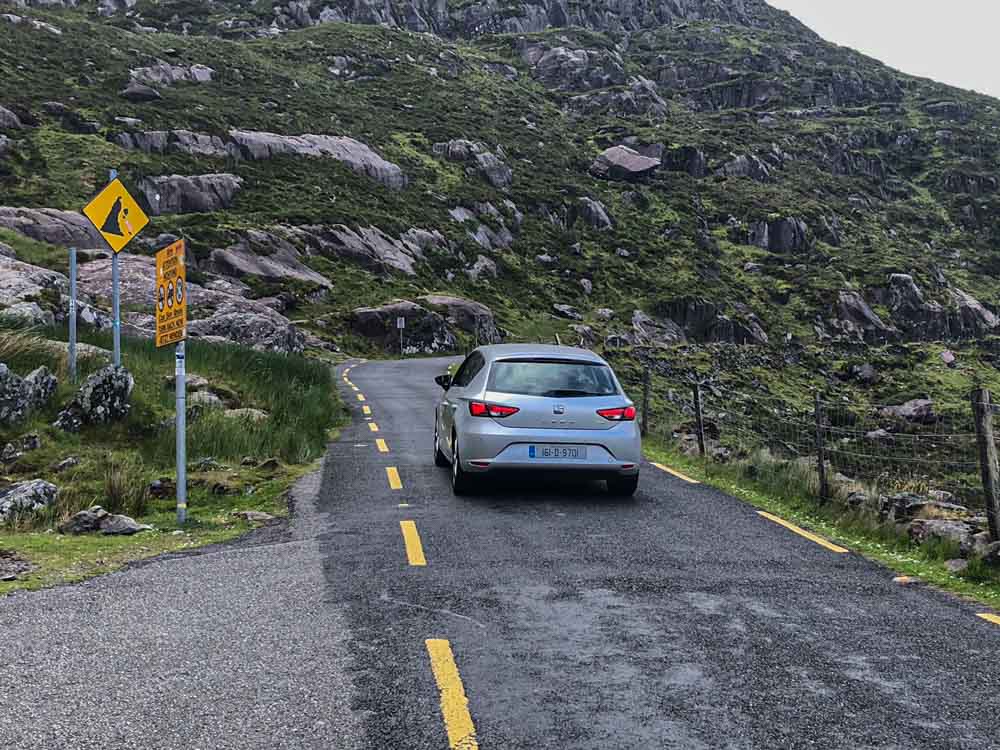 Self Drive in Ireland on Conor Pass. Single car driving on a narrow road.