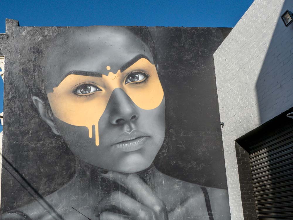 Melbourne street art mural by Fin Dac. Grey woman with yellow mask