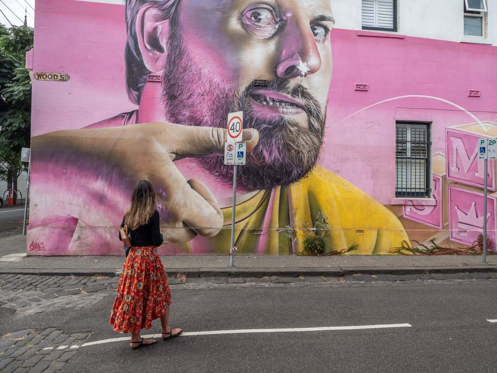 Melbourne mural in Fitzroy by Smug. Man with yellow shirt and pink background.