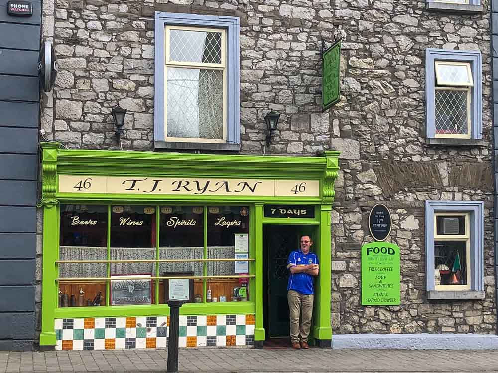 TJ Ryan's Pub in Cashel Ireland. Man in front of green doorway with rock wall