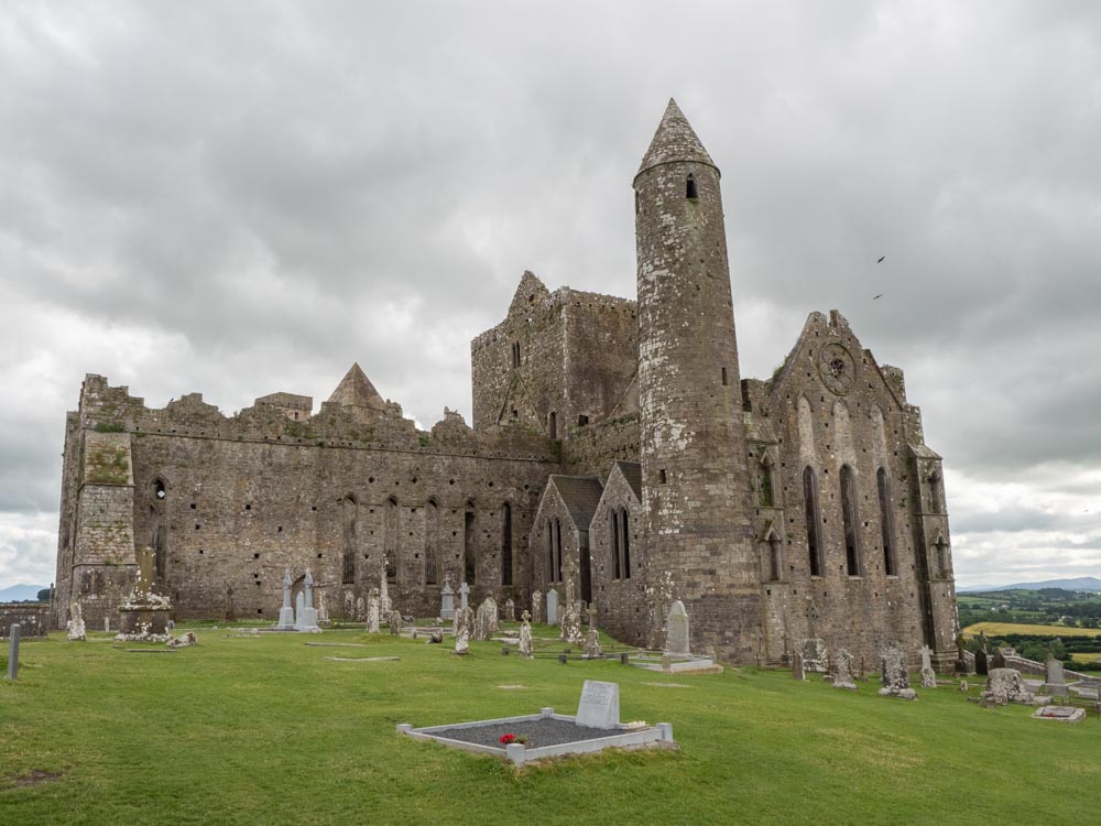Ireland by Car: Rock of Cashel. Stone castle ruin with gravestones