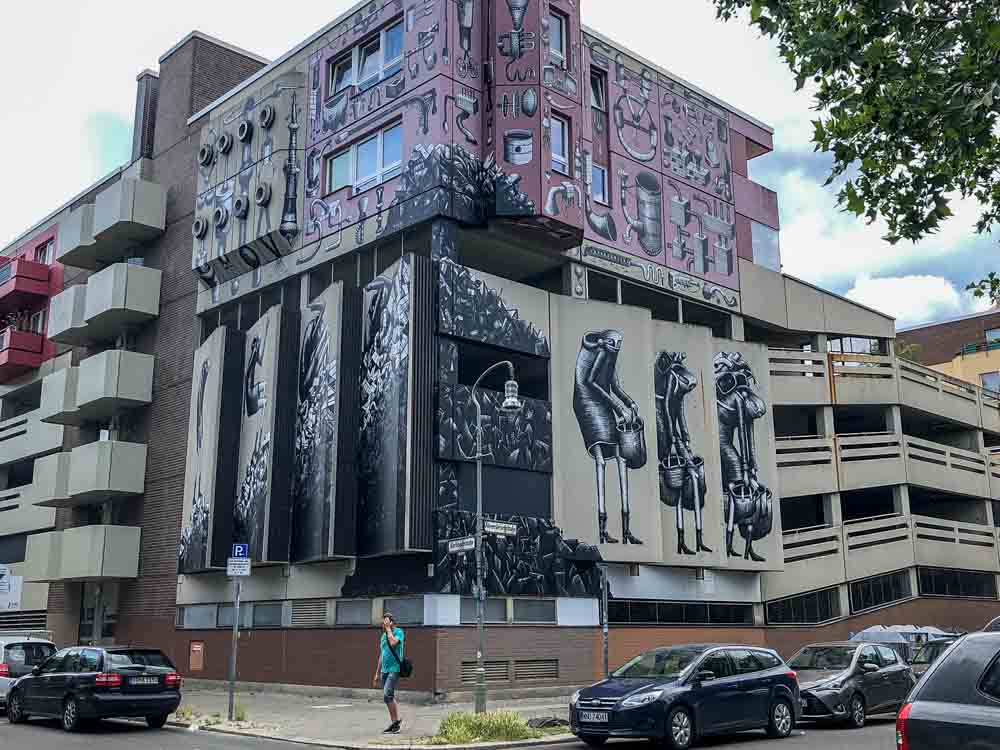 Street art Berlin mural by Phlegm. Black figures and pink mural
