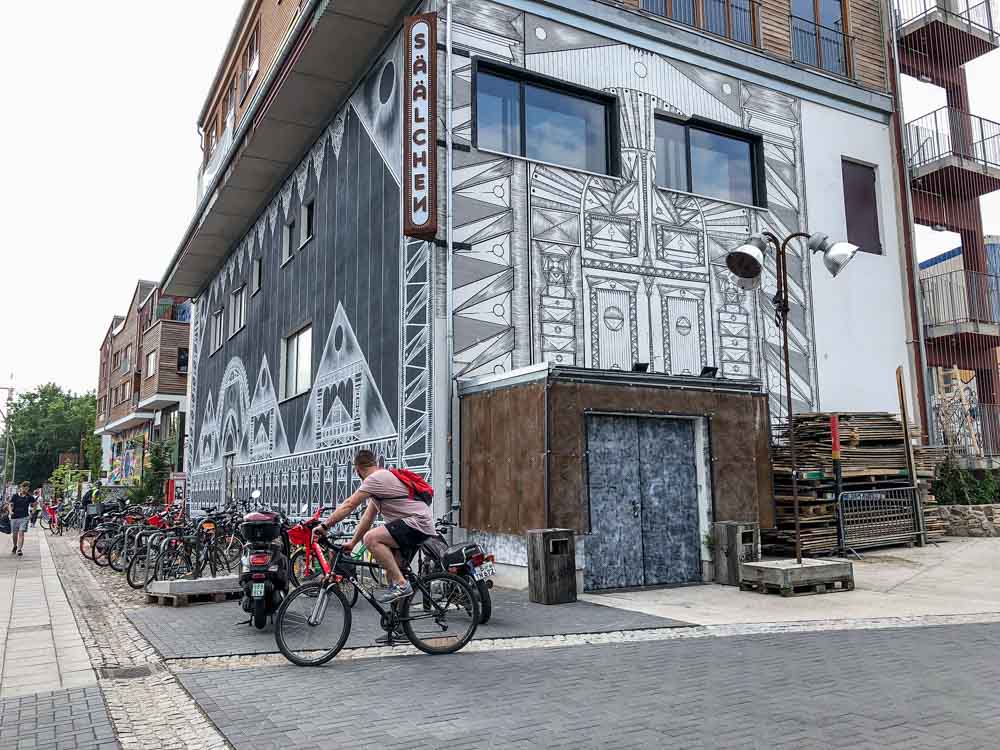 Berlin murals near Holzmarkt. man on bicycle and black and white mural.