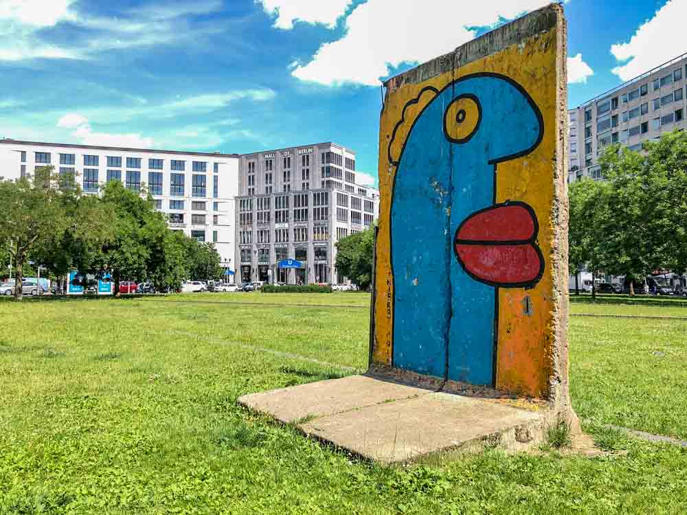 Berlin wall painted mural by Thierry noir. blue head and red lips on yellow background