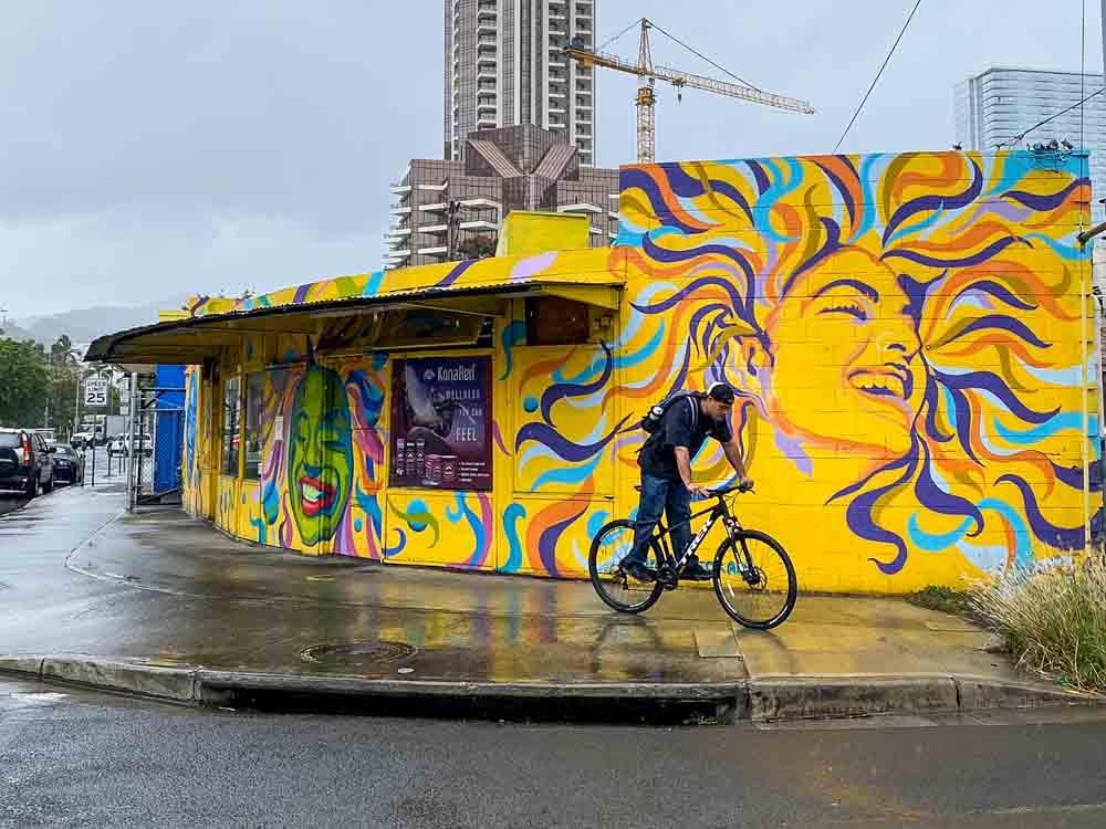 Ran Novek mural in Kaaka'ako Hawaii, Yellow building with man on bike