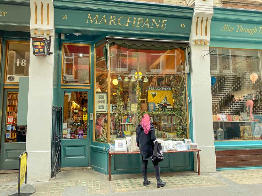 London Bookshops: Cecil Court Marchpane books. Woman with pink hair and green shopfront