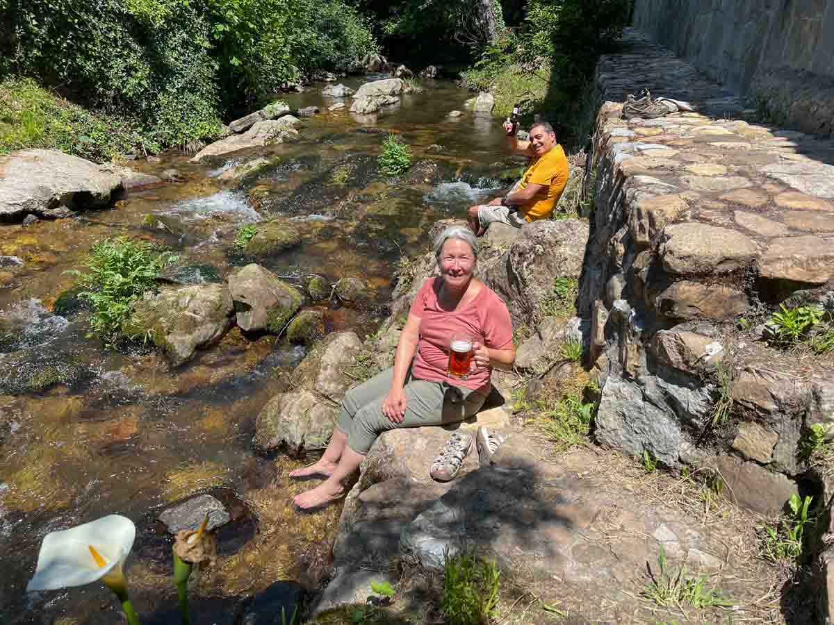 Camino Primitivo stream bed with beer. soaking feet in stream