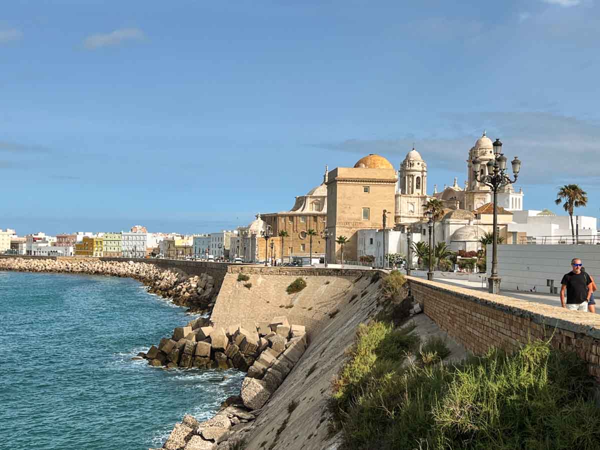 Seawall promenade on Cádiz day trip, with old buildings and ocean.